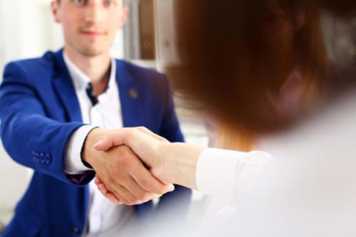 Man in suit shake hand as hello in office closeup